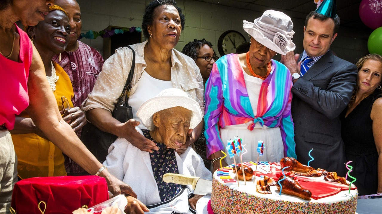 An elderly woman blows out birthday candles
